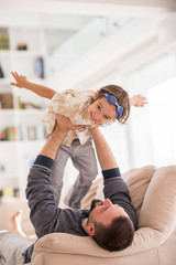 Father playing with his little son on sofa at home