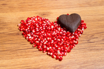 Heart of red pomegranate seeds and dark chocolate - a declaration of love on Valentine's Day.