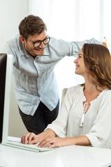 Obraz premium Collegues smiling while using computer at office