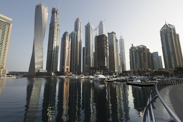 Fototapeta premium Architecture theme. Panoramic view with modern skyscrapers and water pier of Dubai Marina at sunrise,, United Arab Emirates. Luxurious property.