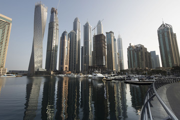 Fototapeta na wymiar Architecture theme. Panoramic view with modern skyscrapers and water pier of Dubai Marina at sunrise,, United Arab Emirates. Luxurious property.