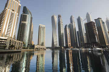 Fototapeta na wymiar Architecture theme. Panoramic view with modern skyscrapers and water pier of Dubai Marina at sunrise,, United Arab Emirates. Luxurious property.