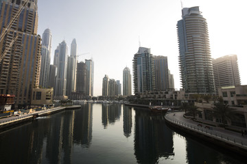 Fototapeta na wymiar Architecture theme. Panoramic view with modern skyscrapers and water pier of Dubai Marina at sunrise,, United Arab Emirates. Luxurious property.