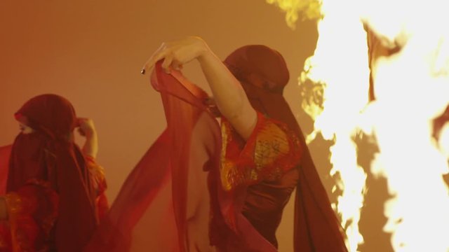 Beautiful traditional asian belly dancer. Asian girl dancing on red background. Studio shoot with fire. Shot on RED EPIC DRAGON Cinema Camera in slow motion.