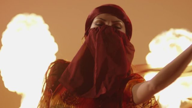 Beautiful traditional asian belly dancer. Asian girl dancing on red background. Studio shoot with fire. Shot on RED EPIC DRAGON Cinema Camera in slow motion.