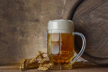 beer mug with wheat ears and wooden barrel on a dark wall background, pour beer 