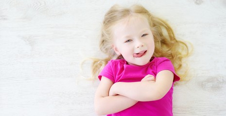 Little girl lying on white wooden floor