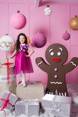 Brunette girl child 5 years old in a pink dress. in holiday rose quartz room with gifts.