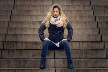 Junge blonde Frau sitzt auf einer Treppe