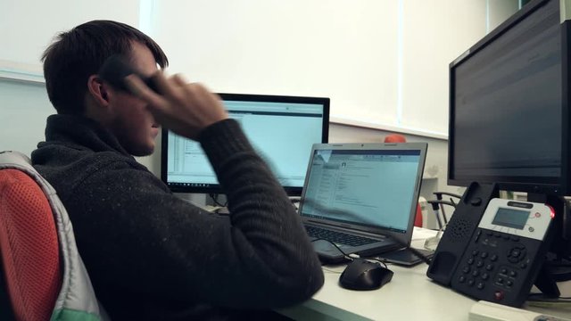 Helpdesk Service Representative Answers the Phone in Front of Three Screens