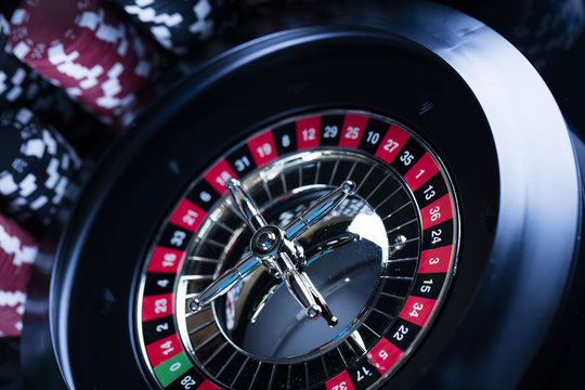 Casino theme. High contrast image of casino roulette, poker game, dice game, poker chips on a gaming table, all on colorful bokeh background. Place for typography and logo.
