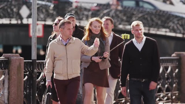 Tourist group with guide move along river embankment on background of historical city center