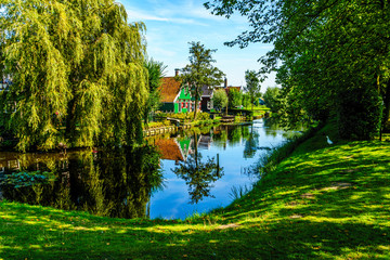 Fototapeta premium Traditional Houses reflecting in the Canal in the Historic Village of Zaanse Schans on the Zaan River in the Netherlands