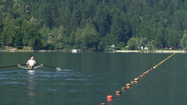 Male athlete rowing on tranquil lake, professional boat racing, competition