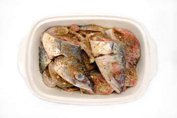 Blue mackerel slices and heads in marinade with herbs
