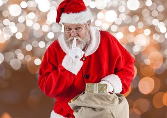 Santa claus with finger on lips holding gift bag