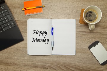 Open notebook with text "Happy Monday" and a cup of coffee on wooden background.