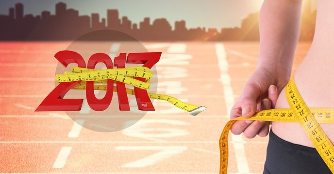 Mid section of woman measuring her waist against 2017