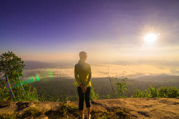 Happy Young Woman Hiker With Open Arms Raised at Sunset on Mountain Peak