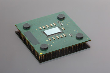 CPU. Modern computer processor unit. The microprocessor is located on a green PCB. 4 mounting pads on the card and microelements around the processor chip. Isolated on gray. Pins reflection