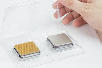 Man's hand opening a box with a CPU. Next to it is another open box with a processor. The second processor is turned upside-down. Isolated on white background.