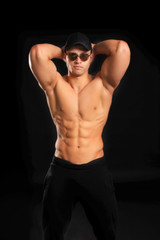 handsome bodybuilder man with a naked torso showing muscles in cap and glasses