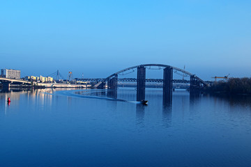 KYIV, UKRAINE – 16 November 2016: Morning view to the unfinished bridge. City landscape. Motor boat floats on the Dnieper 