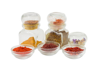 Several various spices in small glass bowls and small jars