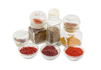 Several various spices in small glass bowls and small jars
