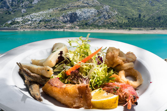 Gegrillter Fisch auf einem wei&szlig;en Teller im Hintergrund ein See