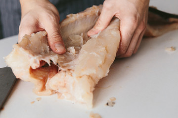 Male cook in the kitchen cut the pike.
