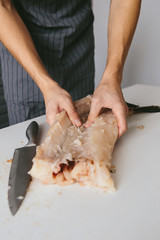 Male cook in the kitchen cut the pike.