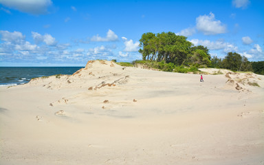 Girl goes through the picturesque sand dunes to the sea