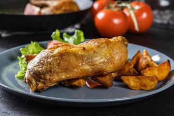 Roasted chicken legs with potato wedges and tomatoes