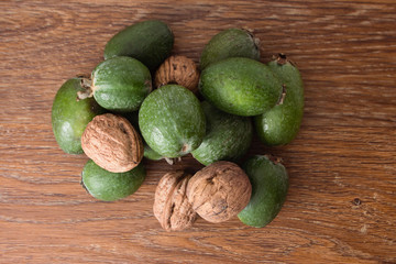 Feijoa fruit and walnuts on wooden background