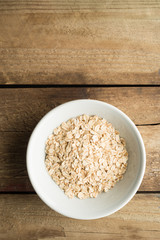 Bowl of Raw Oatmeal on Wooden Background with copy space