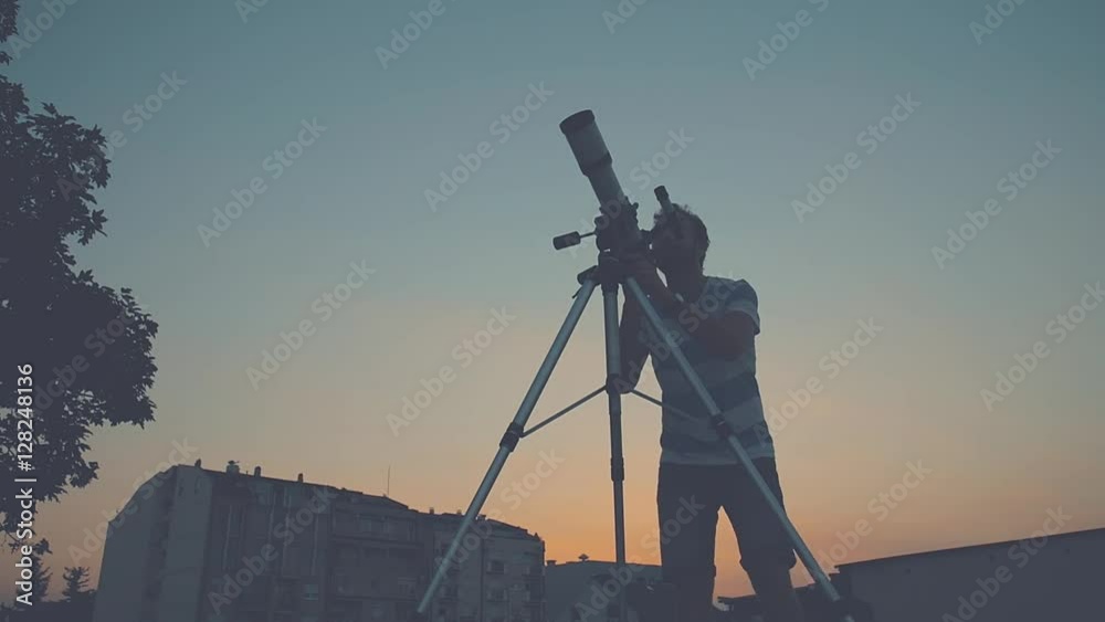 Wall mural man looking through a telescope.