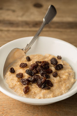 Bowl of Porridge and raisins on Wooden Background