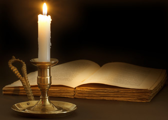 Old book lit by the flame of a candle