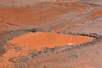 Dirty pool with the red earth on the road to the pits in India 