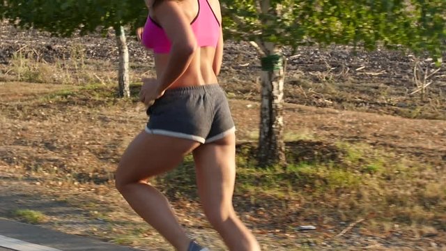 Girl with a beautiful figure running along the road. Slow motion
