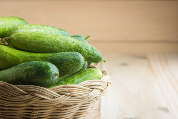 Fresh cucumbers in basket on wood