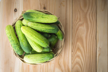 Fresh cucumbers in basket on wood