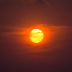 Summer sunset. The setting sun in a cloudy sky background