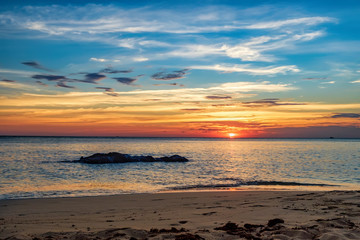 Coast of the sea at colorful sunset, Koh Chang, Thailand. Beach sunset is a golden sunset sky with a wave rolling to shore as the sun sets over the ocean horizon