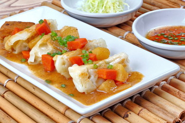 Close up steamed stuffing flour wrap pork topped yellow curry.