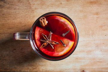 Hot mulled wine with spices on wooden table, from above