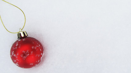 Winter background, red Christmas ball in the snow