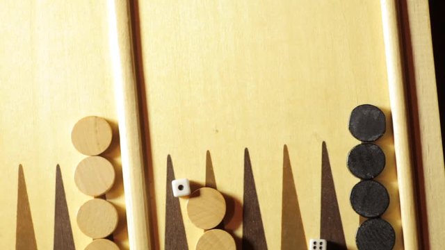 Panning shot of a backgammon board with some rolling dice.