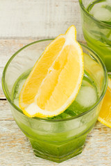 green cocktail with tarragon and lemon wedges